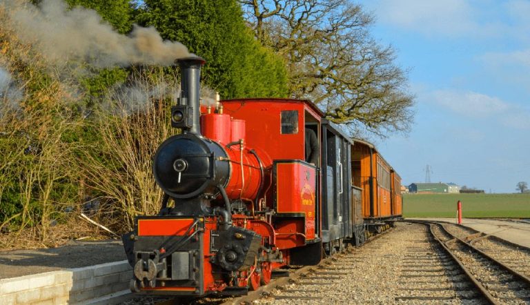 Red-Train-sunny-day-with-trees-coming-towards-camera